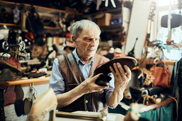 Senior male shoemaker restoring a shoe in his old workshop in the city