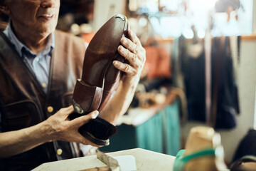 Senior male cobbler restoring a shoe in his old workshop in the city