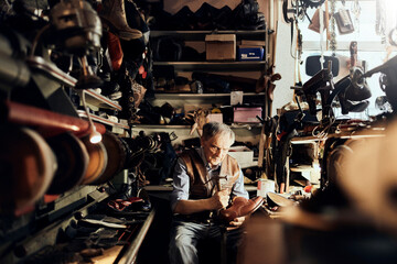 Senior male shoemaker restoring a shoe in his old workshop in the city