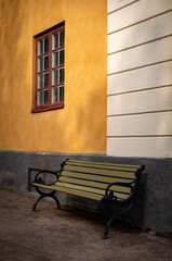 green park bench in front of yellow white wall