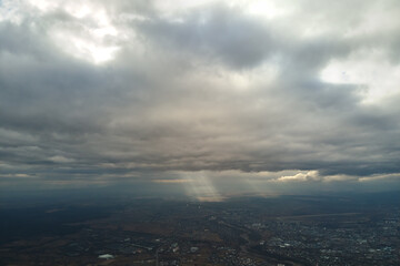 Aerial view from high altitude of distant city covered with puffy cumulus clouds forming before...