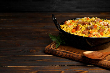 Delicious pilaf with meat and carrot served on wooden table. Space for text
