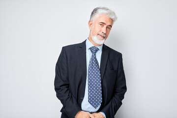 Portrait of confident mature businessman with serious face and gray hair isolated on studio background. Good looking 60 year old man, boss in suit.