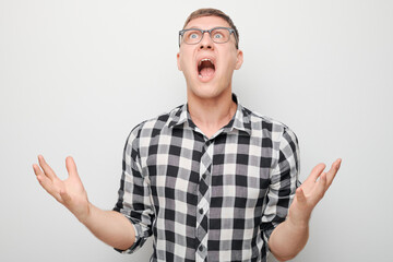 Naklejka premium Portrait of angry young man screaming holding hands in furious gesture isolated on white studio background. Devil boss face. Human emotions, facial expression concept