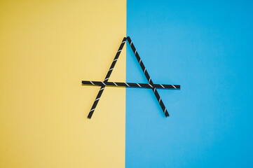Letter A made from black straws on a colorful background. Flat lay.