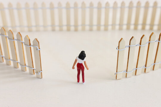 Concept image of a woman encountering an obstacle of a fence and thinking how to overcome it
