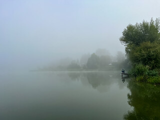 Mystical morning at the fog-kissed lake, where nature's beauty emerges through the ethereal mist.