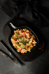Eggs with vegetables. Scramble with vegetables on a dark background.