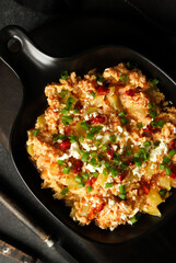 Eggs with vegetables. Scramble with vegetables on a dark background.