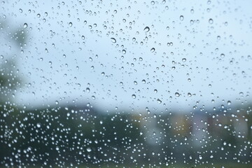 blur background with blue sky and green tree on rainy day, water droplet on mirror