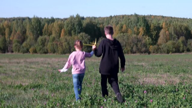 Child runs with toy plane in hand in summer field