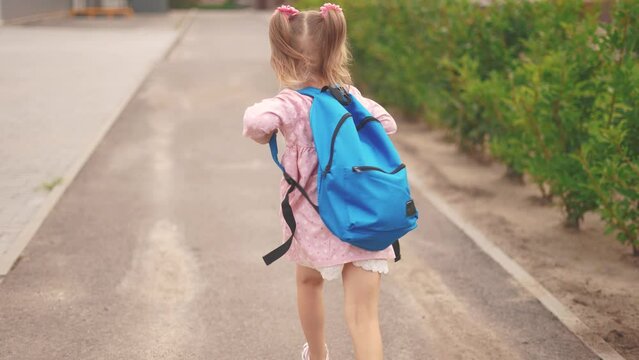 back to school. a child schoolgirl run with a backpack to school in the park along the path. school education learning concept. daughter child view from the back in backpack run in the park lifestyle