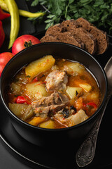 Stewed meat and vegetables in a black plate on a dark background