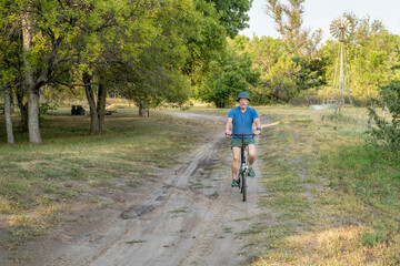 Obraz premium athletic senior man is riding a folding bike in Whitetail Campground in Nebraska National Forest