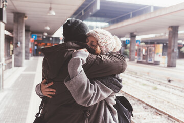 couple standing in train station and embracing