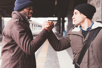 two men holding the hands at the train station