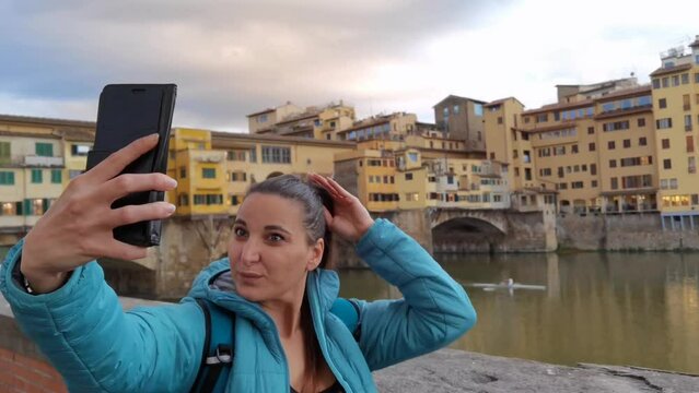 A tourist taking a selfie with her smartphone in front of the Ponte Vecchio in Florence