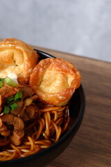 noodles topped with fried egg, green onions, fried shallots