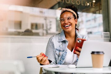 Happy female student sitting in a coffee shop, using a smartphone © (JLco) Julia Amaral