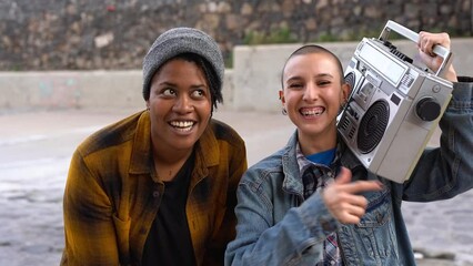 Young multiracial female street musicians rapping and dancing in the city - Bald girl holding vintage boombox stereo
