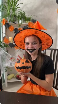 Portrait of a little girl in a hat and a wizard costume for Halloween, a girl in an orange hat for Halloween