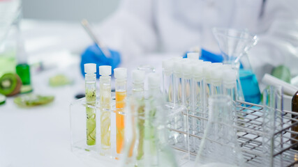 Close up of tissue of avocado, cucumber, kiwi, orange and tomato in test tube. Cosmetic laboratory. Experiment of vitamin in serum, skin care, lotion, treatment, essence and medical body product.