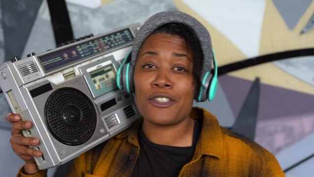 Young african american female street musician rapping in the city while holding vintage boombox stereo
