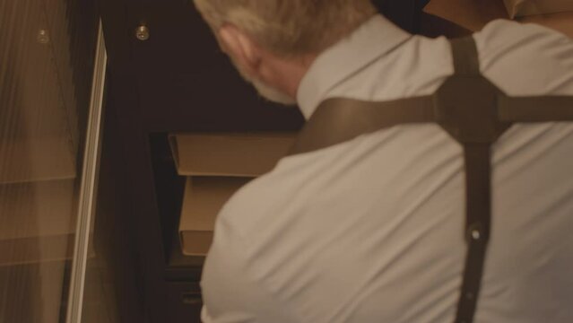 From above shot of mature Caucasian FBI agent taking file folder with criminal case info out of safe, investigating crime and collecting evidence