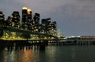 Manhattan, New York City at night. Buildings along west side of Manhattan illuminated against twilight sky. West Side Highway aka Henry Hudson Parkway, park and pier on Hudson River bank.