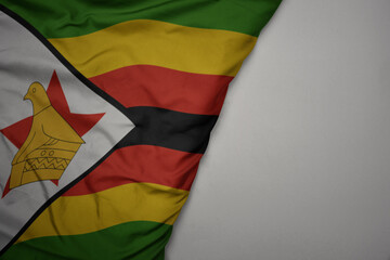 big waving national colorful flag of zimbabwe on the gray background.