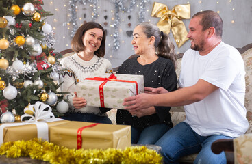 Fototapeta na wymiar Family holding gifts on sofa in christmas interior