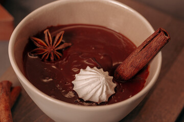 A bowl of hot chocolate with cinnamon and spices on the Christmas table. Hot winter drink