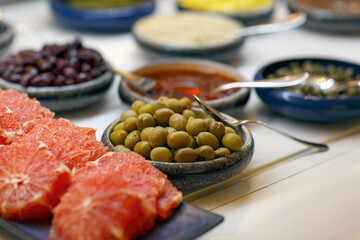 Defocused background of delicious green olives in a wooden bowl on white background. Selective focus with shallow depth of field. Green olives in olive oil. Tasty organic green olives in the plate.
