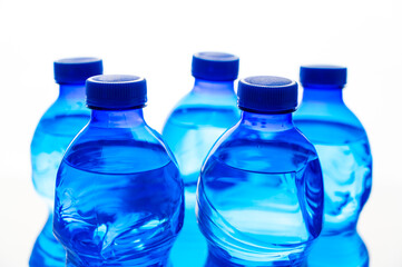 Transparent blue plastic bottles containing water, next to each other. Use and recycling of plastic, environmental protection.