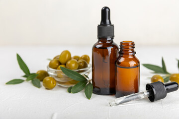 Olive essential oil. Glass bottle with olive oil on a texture table. Olive cosmetic oil. Serum for moisturizing and nourishing skin and hair. Beauty concept. Natural cosmetic. Copy space.spa