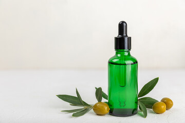 Olive essential oil. Glass bottle with olive oil on a texture table. Olive cosmetic oil. Serum for moisturizing and nourishing skin and hair. Beauty concept. Natural cosmetic. Copy space.spa