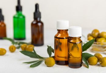 Olive essential oil. Glass bottle with olive oil on a texture table. Olive cosmetic oil. Serum for moisturizing and nourishing skin and hair. Beauty concept. Natural cosmetic. Copy space.spa
