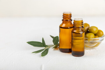 Olive essential oil. Glass bottle with olive oil on a texture table. Olive cosmetic oil. Serum for moisturizing and nourishing skin and hair. Beauty concept. Natural cosmetic. Copy space.spa