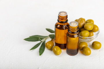 Olive essential oil. Glass bottle with olive oil on a texture table. Olive cosmetic oil. Serum for moisturizing and nourishing skin and hair. Beauty concept. Natural cosmetic. Copy space.spa
