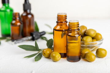 Olive essential oil. Glass bottle with olive oil on a texture table. Olive cosmetic oil. Serum for moisturizing and nourishing skin and hair. Beauty concept. Natural cosmetic. Copy space.spa