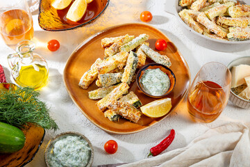 Healthy zucchini fries with yogurt and herbs sauce on a white table