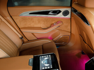 rear seats made of orange leather in the interior of a luxury car with pink ambient lighting