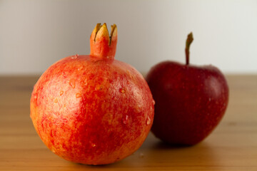 Ripe pomegranate and apple on a wooden table.