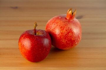 Ripe pomegranate and apple on a wooden table.