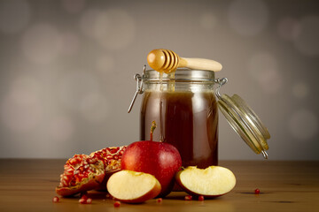 Honey in a jar with apple and pomegranate on wooden table