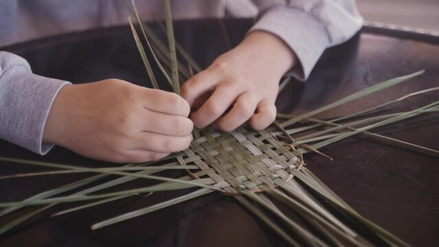 Close-up on the hands of an artisan who uses natural materials to make traditional items.