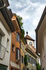 Street in the historical centre of Freiburg, Baden-Wurttemberg, Germany. The tower of the entrance gate of the city on the background.
