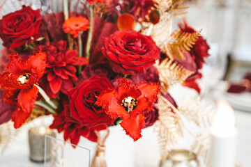 Red gold golden color decor, floral arrangement. Festive bouquet, table decoration. Traditional Chinese New Year party restaurant celebration. Roses,poppies,fan,candles,tassels.Chinese lunar calendar