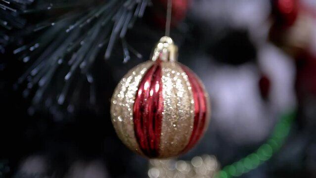 Golden Shiny Christmas Tree Ball Hanging on Branch on a Blurred Background. Close up. Rotation. Christmas tree decoration bauble. Christmas decoration. isolated. Positive emotion. Happy New Year.