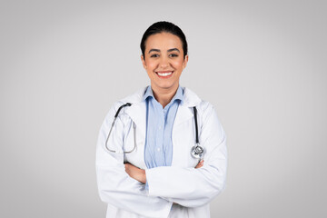 Healthcare concept. Portrait of young latin woman doctor posing with folded arms and smiling at...